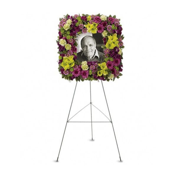 Floral funeral wreath on an easel with a portrait in the center