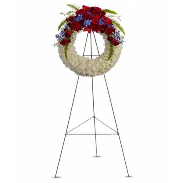 Standing floral wreath with red, white, and blue flowers on an easel