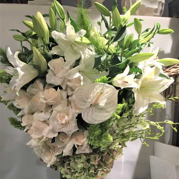 White lilies and pale roses arranged in a tall dark vase