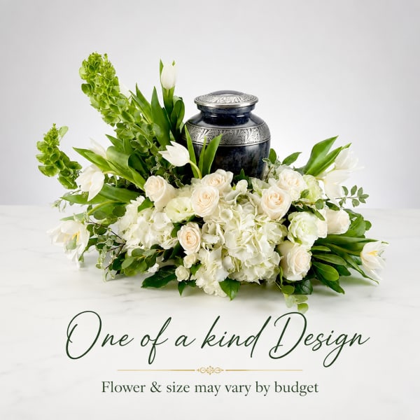 White floral arrangement with roses, hydrangeas, and tulips around a dark urn