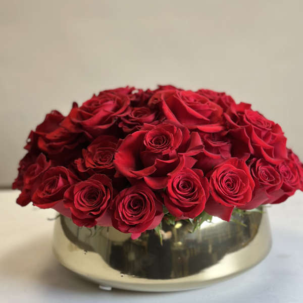 Red roses arranged in a low gold bowl