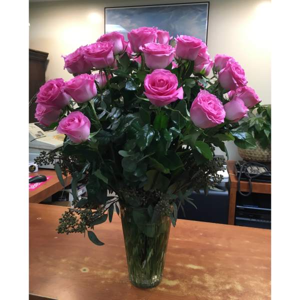 Pink roses arranged in a tall glass vase