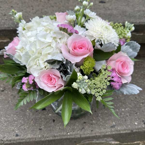 Pink roses and white flowers arranged in a glass vase