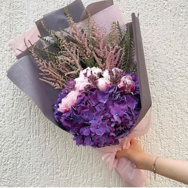 Purple hydrangea bouquet with pink flowers wrapped in gray and pink paper