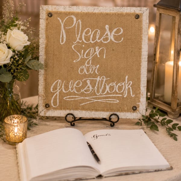Guest book sign beside white roses and lanterns