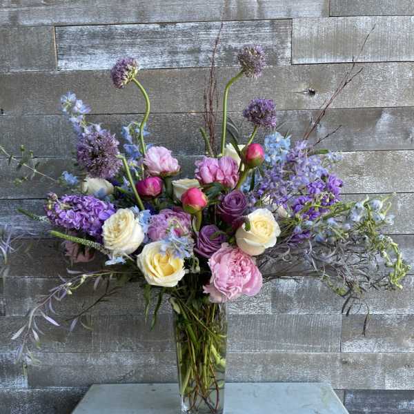 Tall mixed bouquet of pink, purple, and white flowers in a glass vase