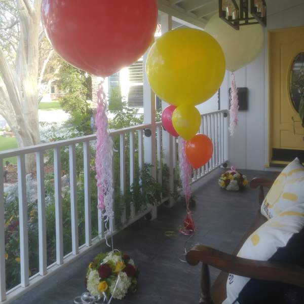 Large balloons and small flower arrangements decorate a porch.