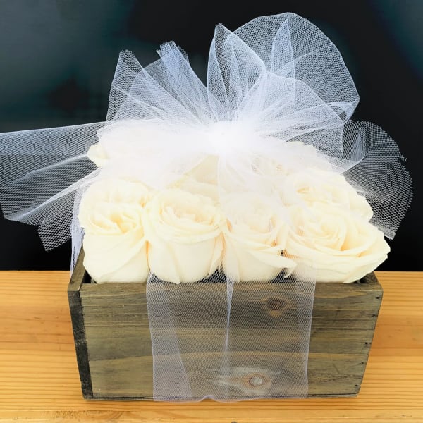White roses in a rustic wooden box with a sheer tulle bow