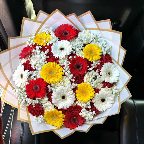 Bouquet of red, yellow, and white gerbera daisies wrapped in white paper