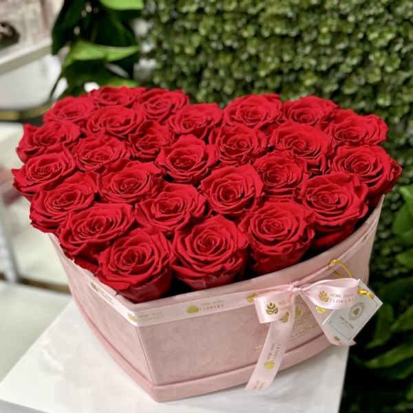 Heart-shaped blush box filled with red roses on a white pedestal