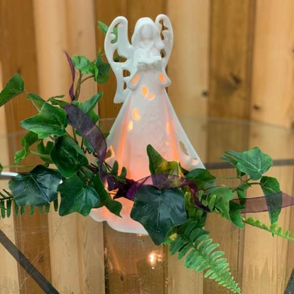 White angel figurine with glowing light and ivy garland