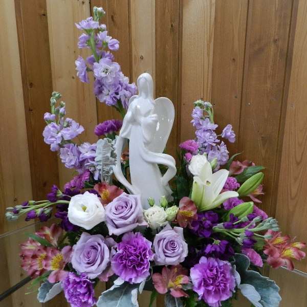 Purple and white floral arrangement with an angel figurine