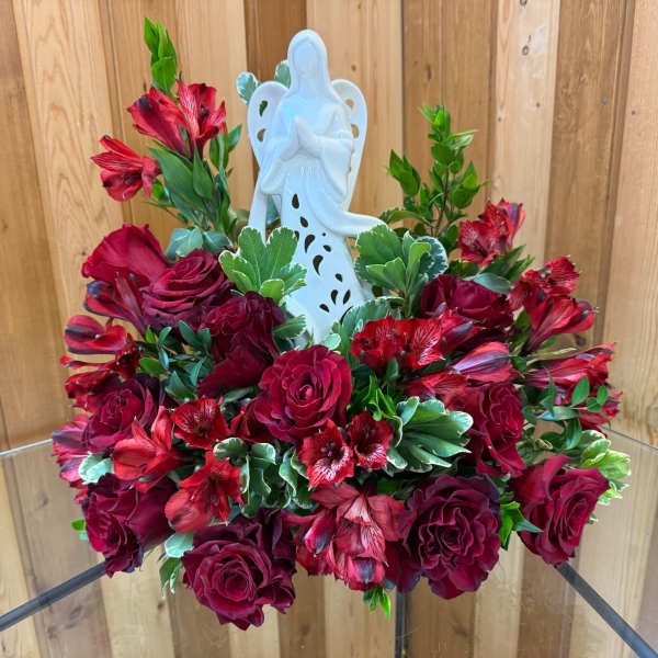 Red rose arrangement with a white angel figurine centerpiece