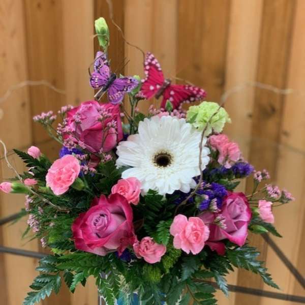 Pink roses and carnations with a white gerbera daisy in a patterned vase