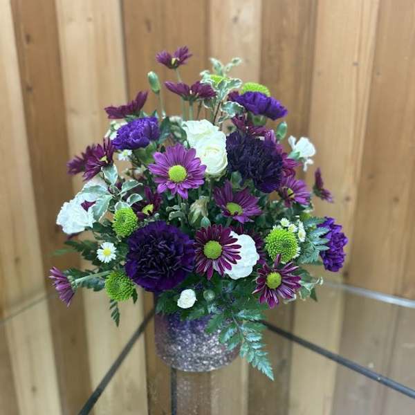 Purple and white flower arrangement in a glittery vase