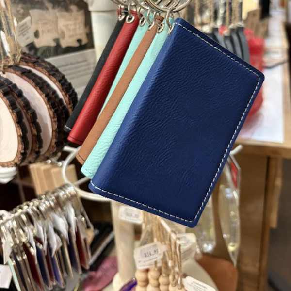 Leather keychain wallet cards hang on a display rack in a shop