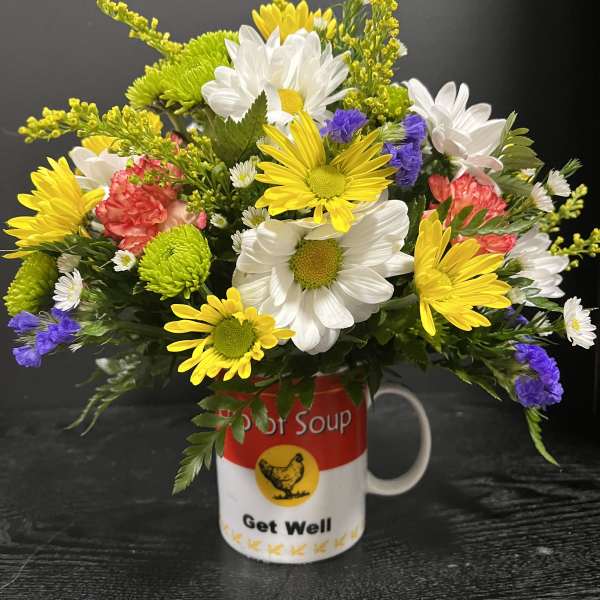 Mixed daisies and carnations arranged in a Get Well mug