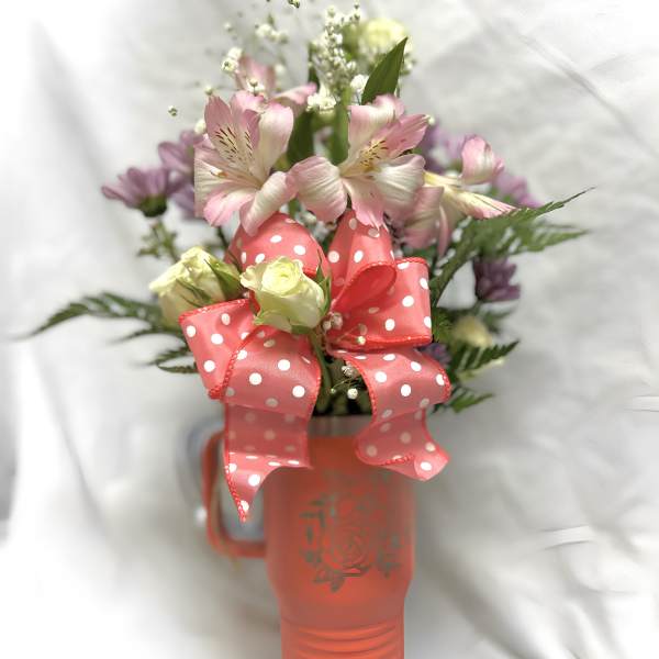 Pink and white flowers in a coral mug with a polka-dot ribbon