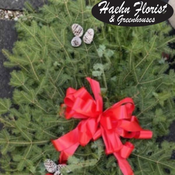 Green wreath with a red bow and small pinecones