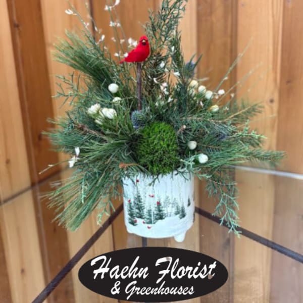 Holiday evergreen arrangement in a white container with a red bird ornament