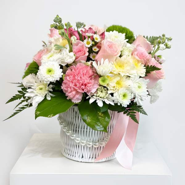 Pink and white mixed bouquet in a white basket with a pink ribbon