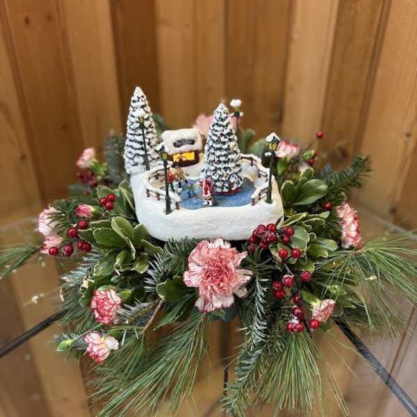 Winter floral arrangement with a miniature ice rink scene and pink flowers