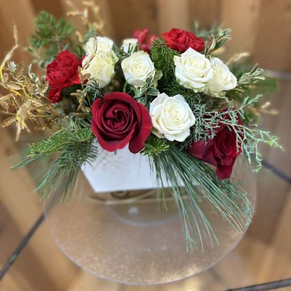 Red and white roses arranged in a clear round vase
