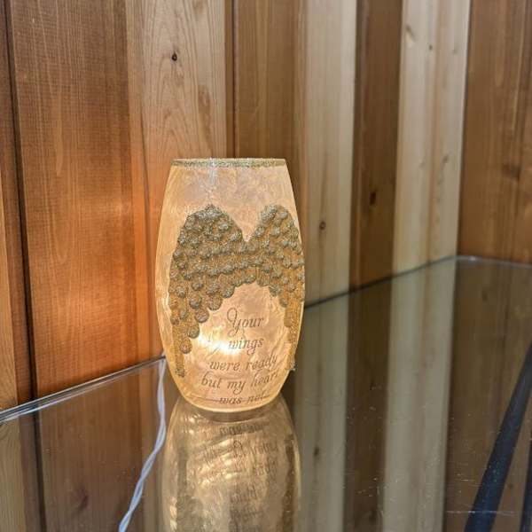 Lit memorial candle with angel wings and a sympathy message