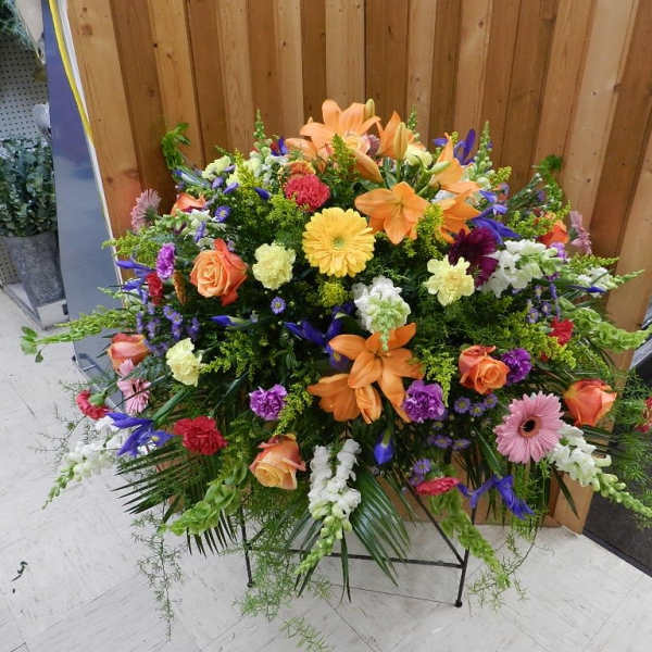 Large mixed floral spray with orange lilies, roses, and gerbera daisies