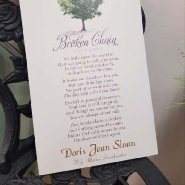 Memorial card with a tree graphic and poem on a black wrought-iron stand