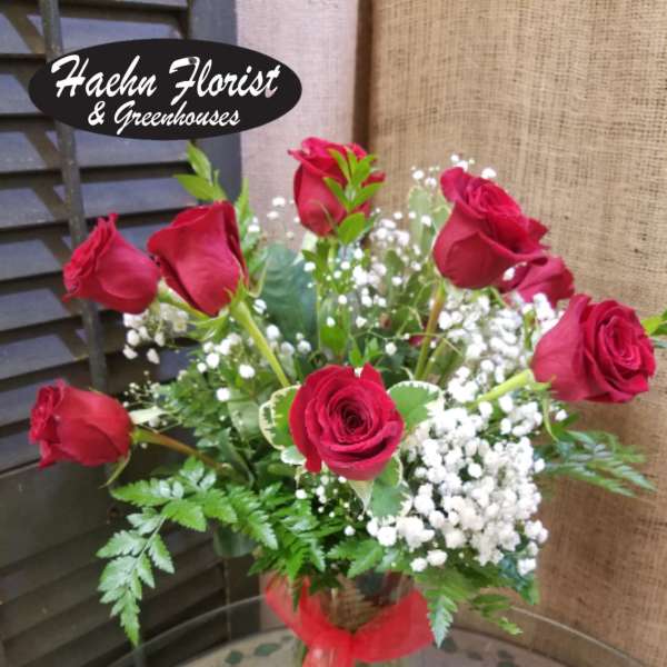 Red roses arranged in a clear glass vase with baby's breath