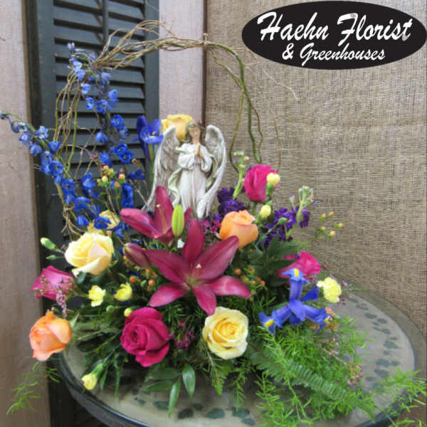 Colorful floral arrangement with roses, lilies, and an angel figurine