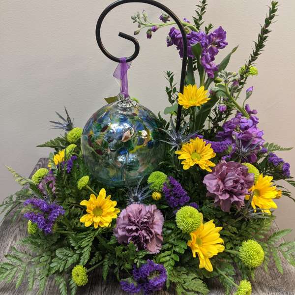 Purple and yellow floral arrangement with a glass ornament centerpiece