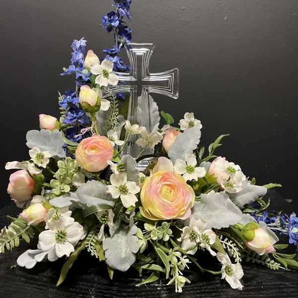 Floral arrangement with a clear cross centerpiece and pastel blooms