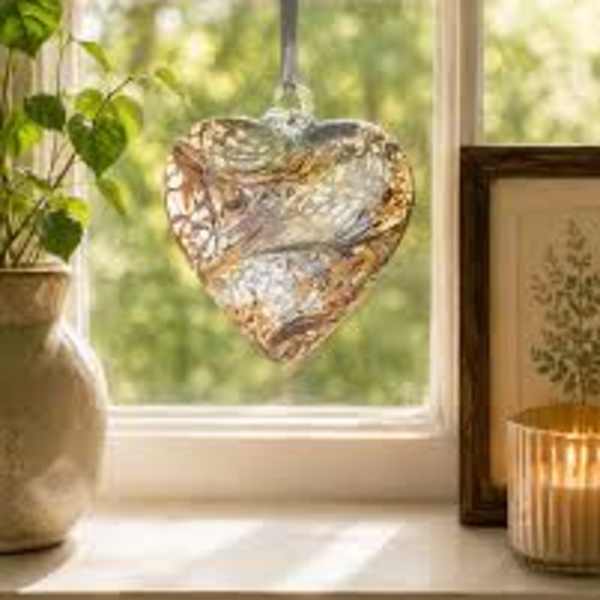 Heart-shaped glass ornament hanging in a sunlit window