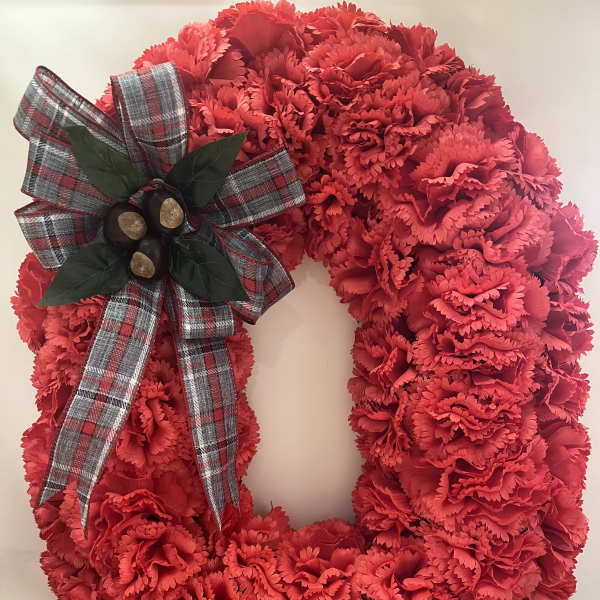 Red carnation wreath with a plaid bow and berry accent