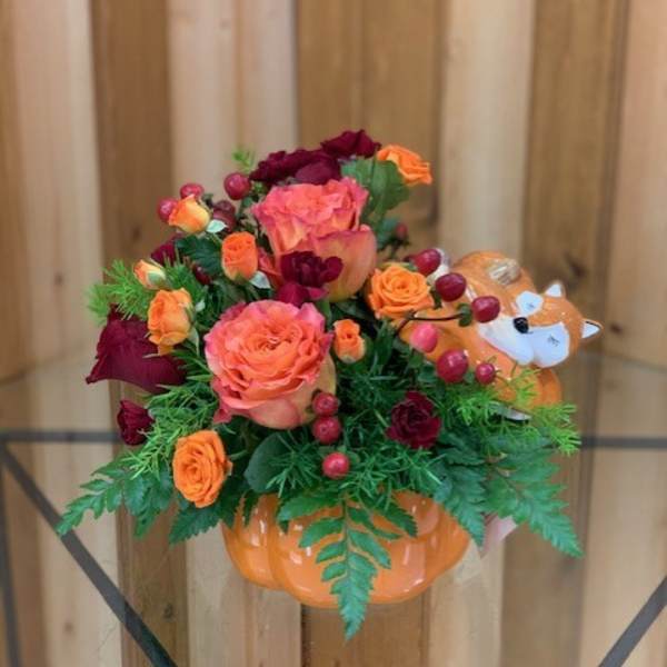 Orange and burgundy rose arrangement in a pumpkin-shaped container