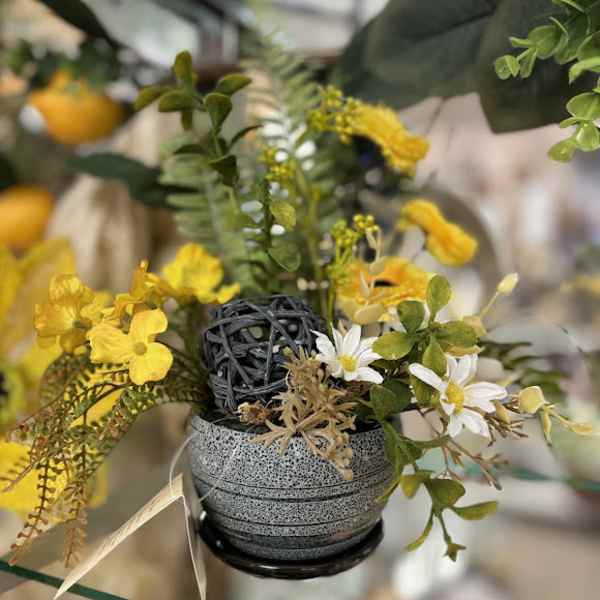 Small floral arrangement with yellow and white flowers in a gray pot