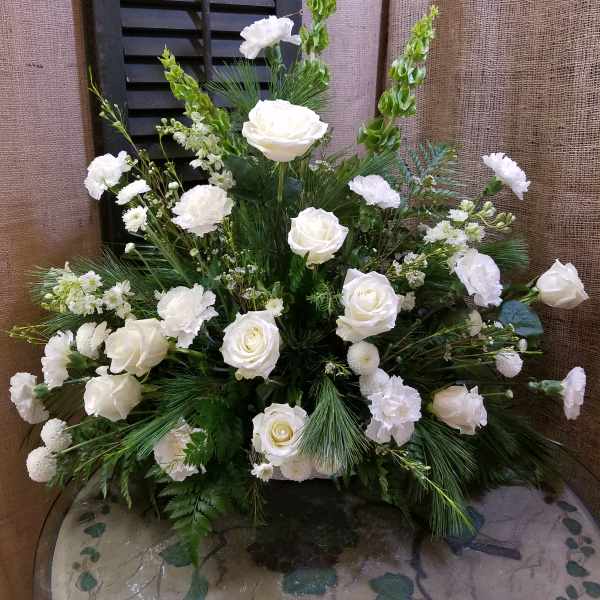 White roses and carnations arranged in a large vase with greenery