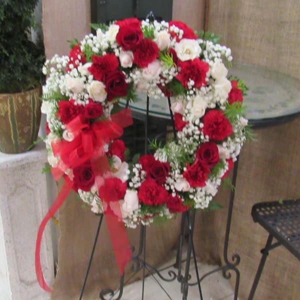 Heart-shaped wreath of red and white roses with a red ribbon