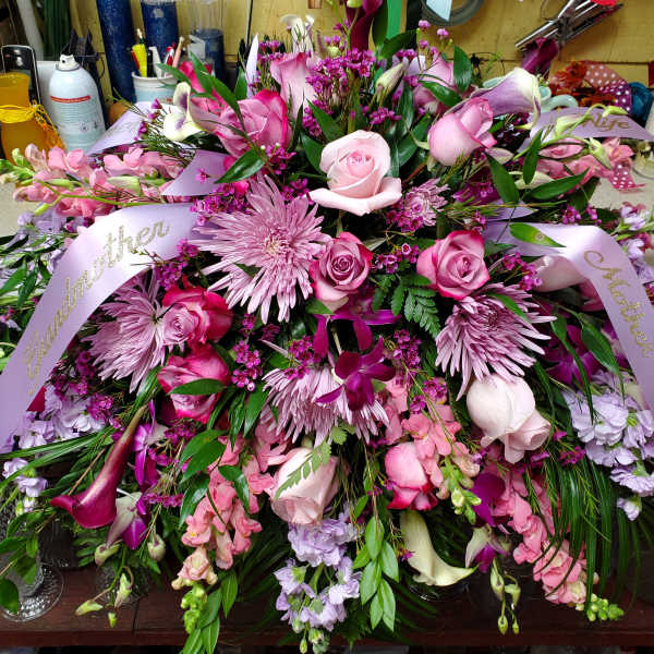 Large pink and lavender floral arrangement with ribbon on a table