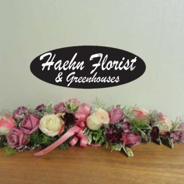 Low floral centerpiece with pink and cream roses and a pink ribbon