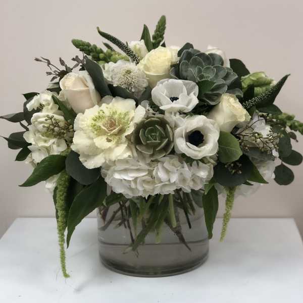 White and pale green floral arrangement in a clear glass vase
