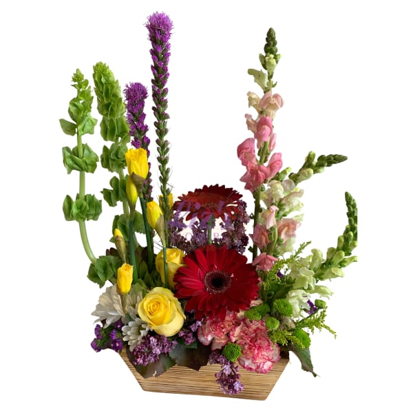 Mixed bouquet in a wooden container with red gerbera, yellow roses, and tall snapdragons