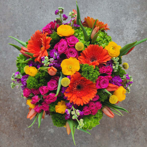 Bright mixed bouquet with orange gerbera daisies, pink roses, and yellow ranunculus