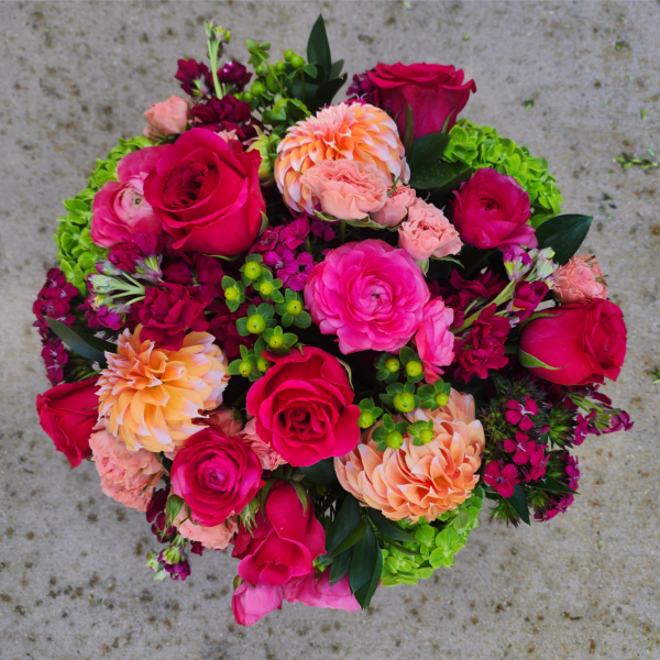 Round bouquet of hot pink and peach flowers with green accents