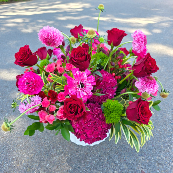 Bouquet of red roses and pink flowers in a white container