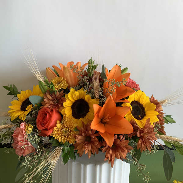 Bouquet of sunflowers, orange lilies, and roses in a white vase