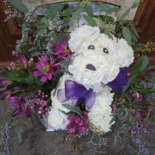 White teddy bear made of flowers with a purple bow and purple blooms