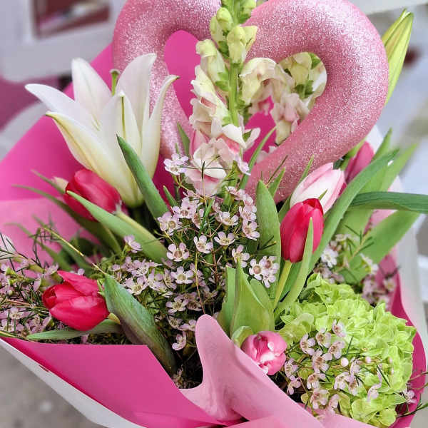 Pink tulips and white lilies in a bright bouquet with a glittery heart pick